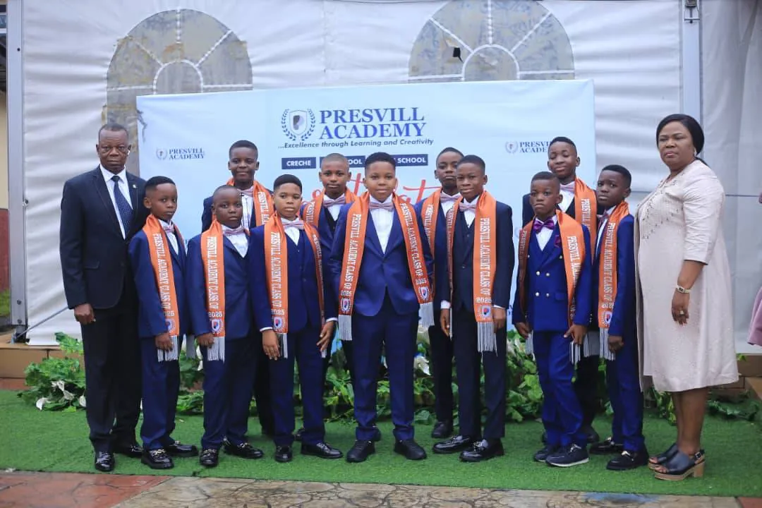 Graduating boys in navy suits and orange sashes in front of the Presvill Academy banner, 2025 graduation