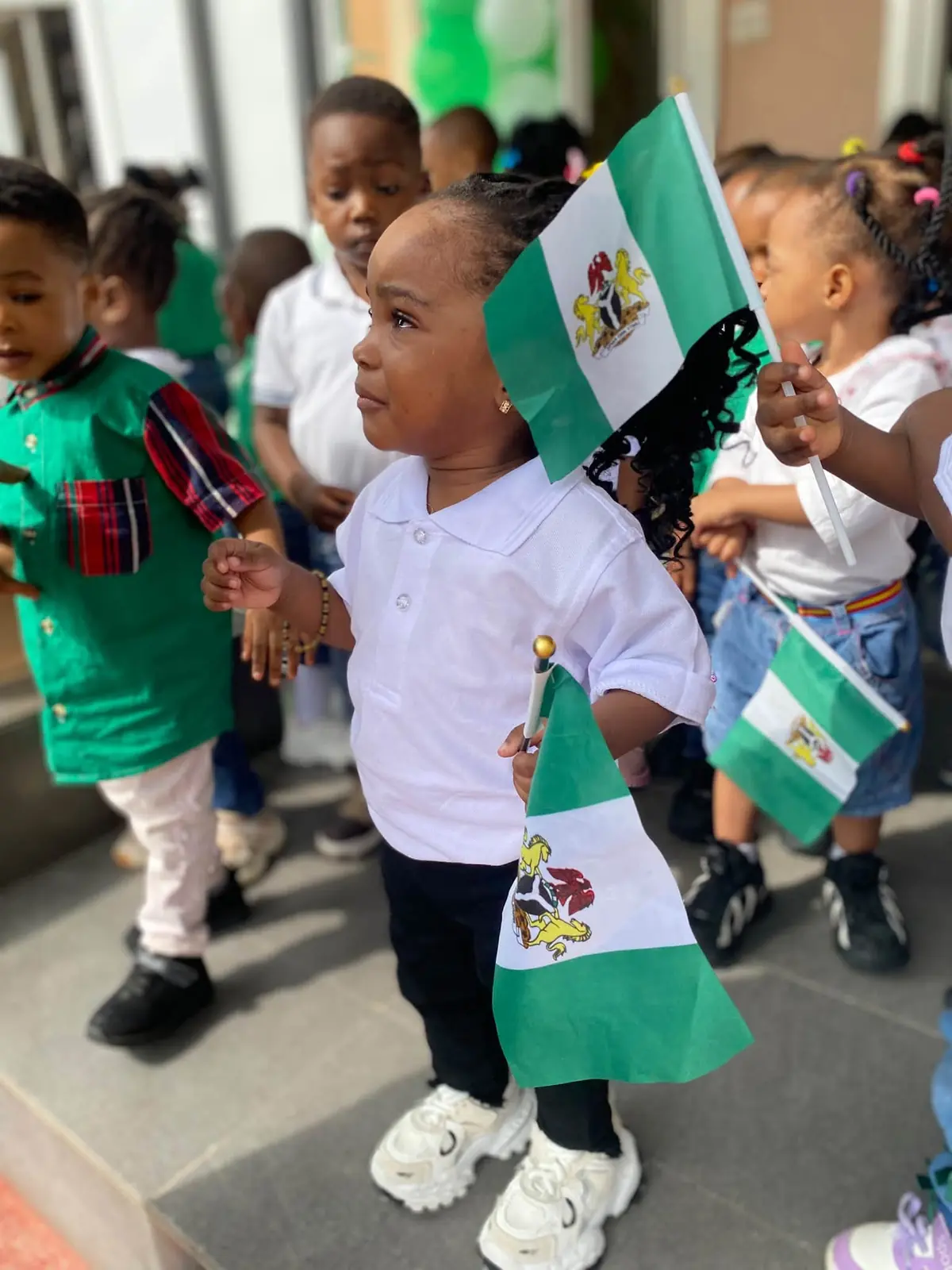 A young pupil holding Nigerian flags for Independence Day