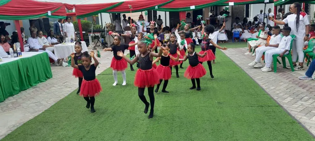 Pupils in red and black dance costumes performing on the lawn at a school celebration