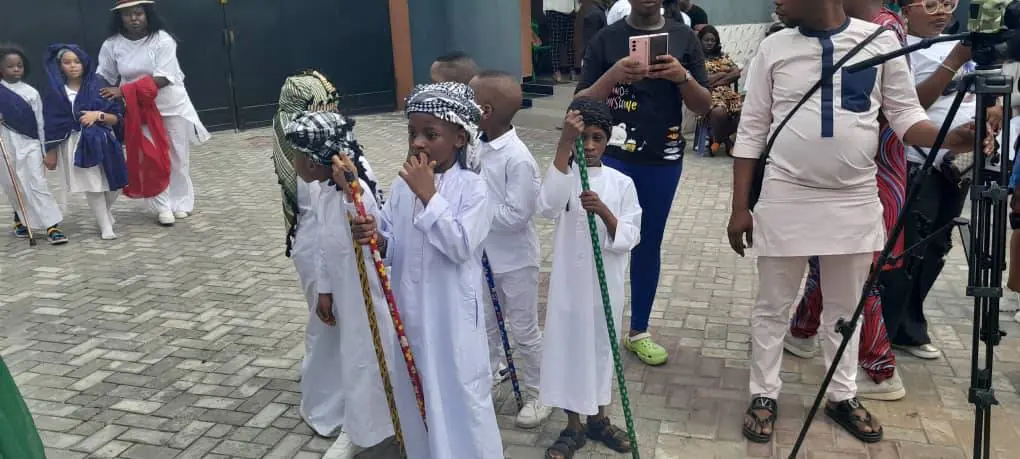 Pupils in white robes and traditional dress at a school celebration
