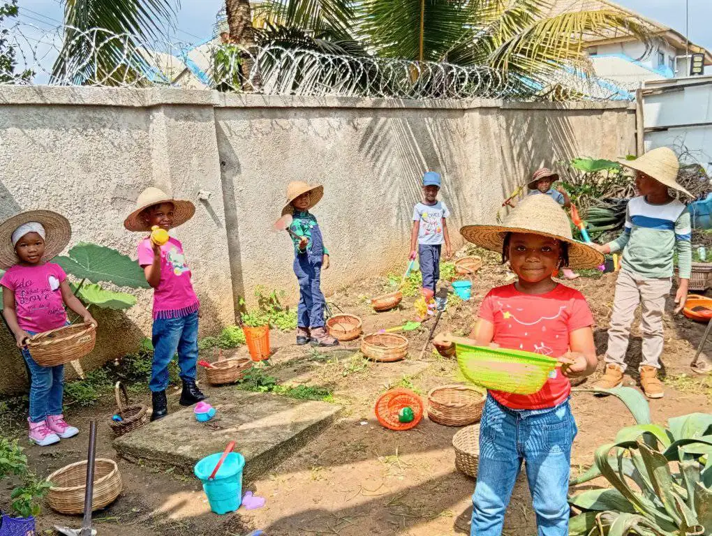 Young pupils in straw hats carrying baskets in the garden