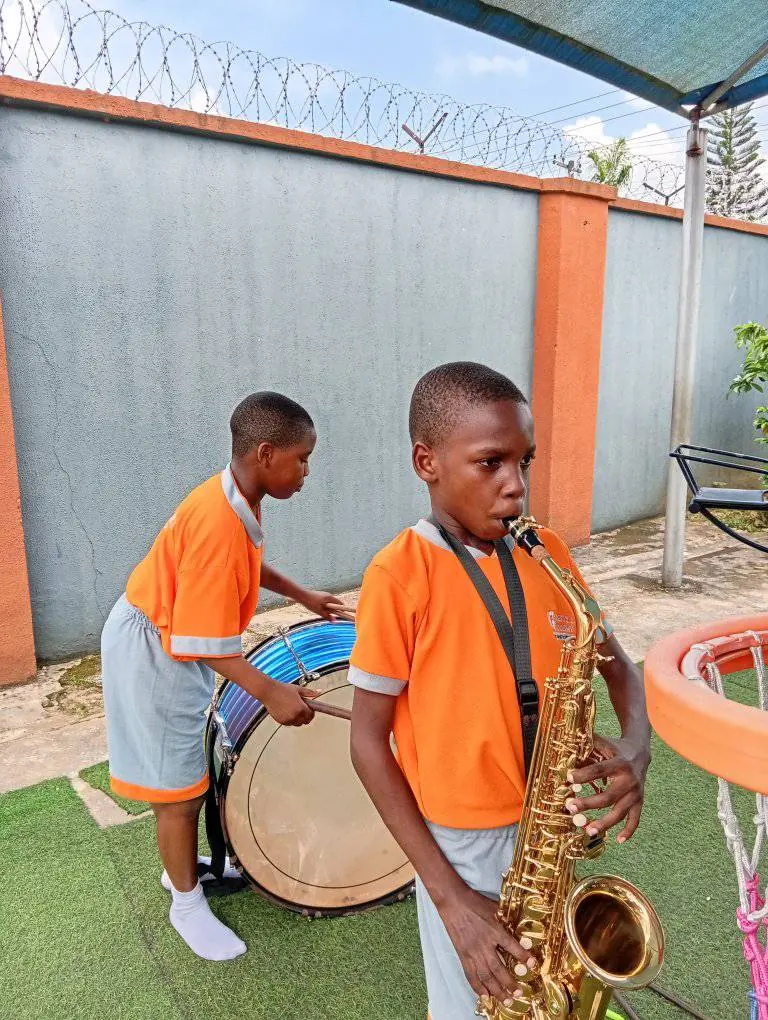Two pupils with a saxophone and a bass drum on the playground