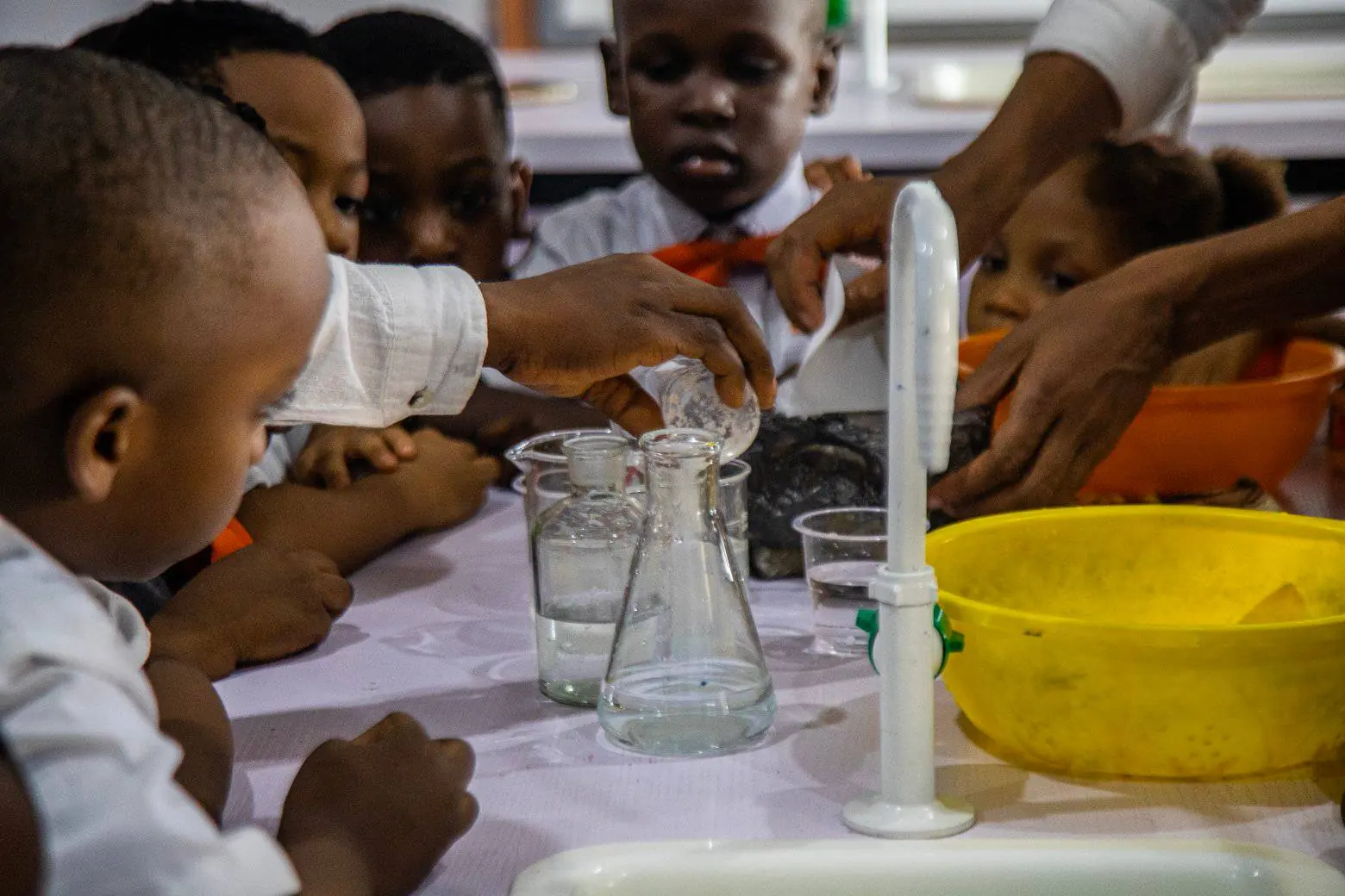 Young pupils pouring liquids at a laboratory bench