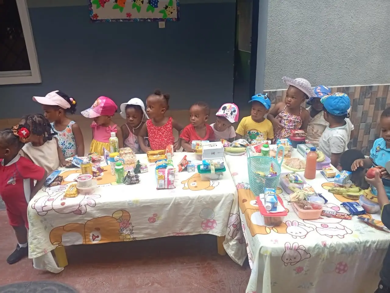 Young pupils in sun hats at a table of snacks on Beach Party Day
