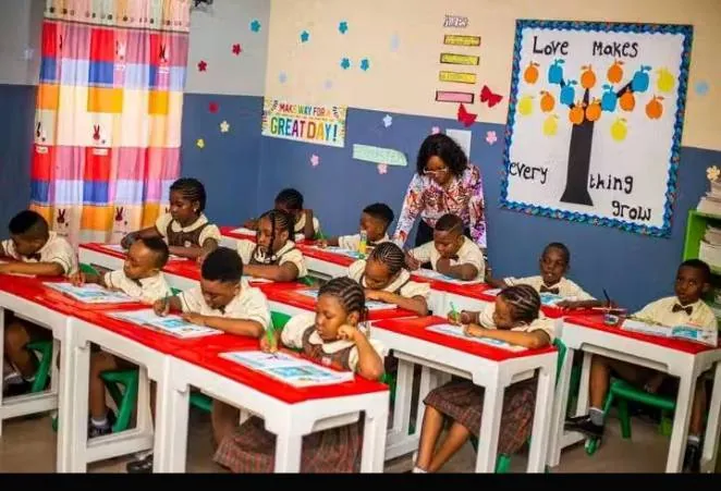 Grade School pupils working at red and white desks beneath a "Love makes everything grow" display