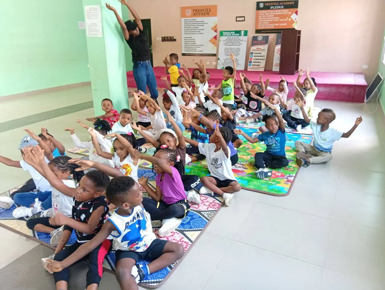 Young pupils stretching on mats during a dance class in the school hall