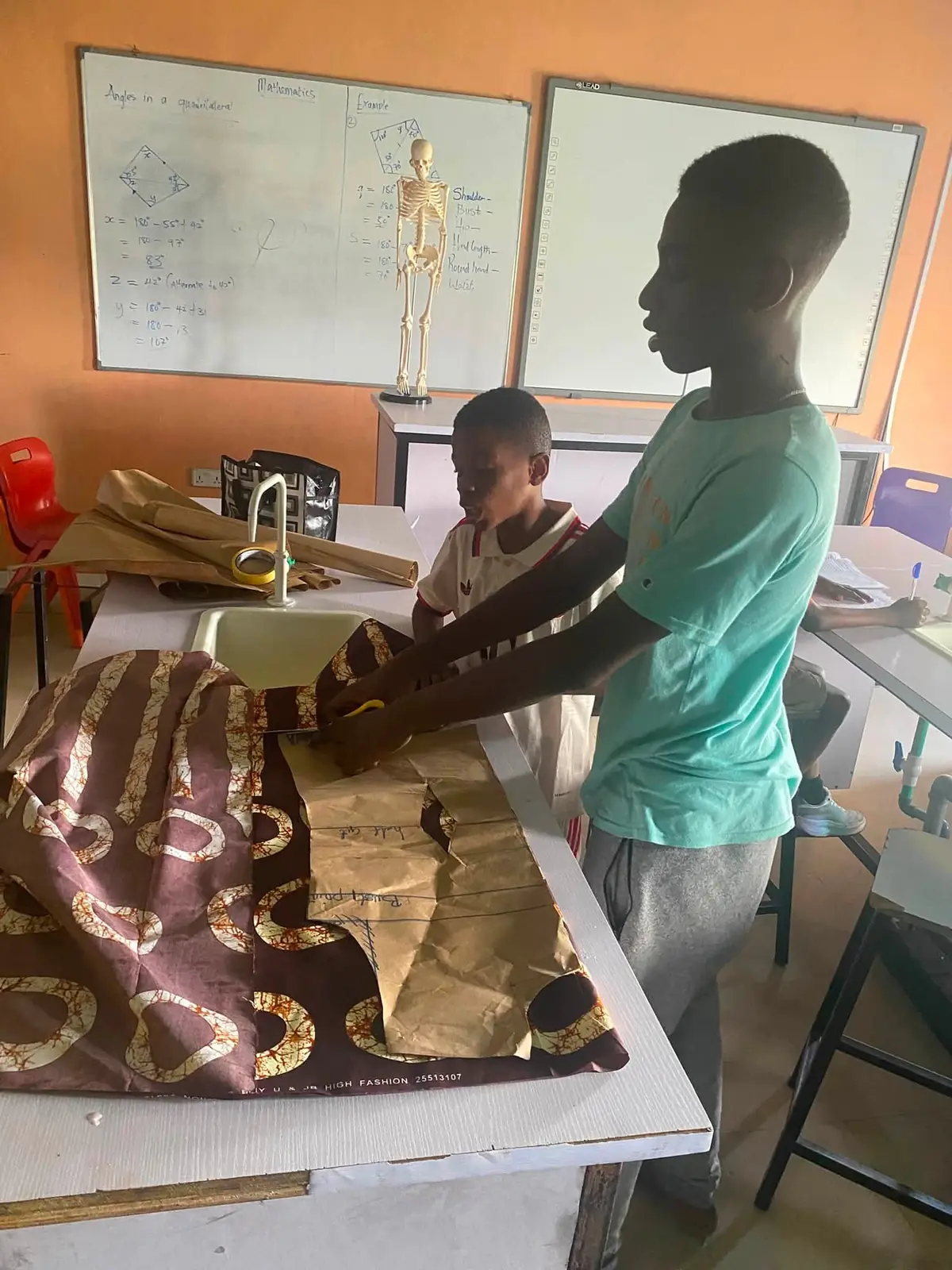 Two pupils laying a paper pattern on patterned fabric