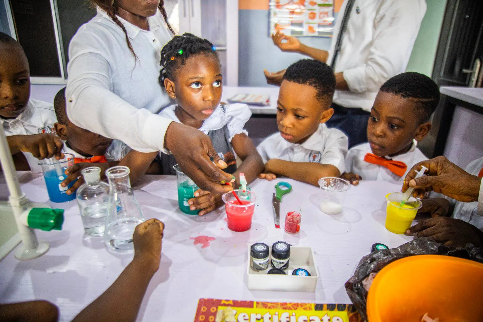 Young pupils mixing coloured liquids in beakers during a science lesson