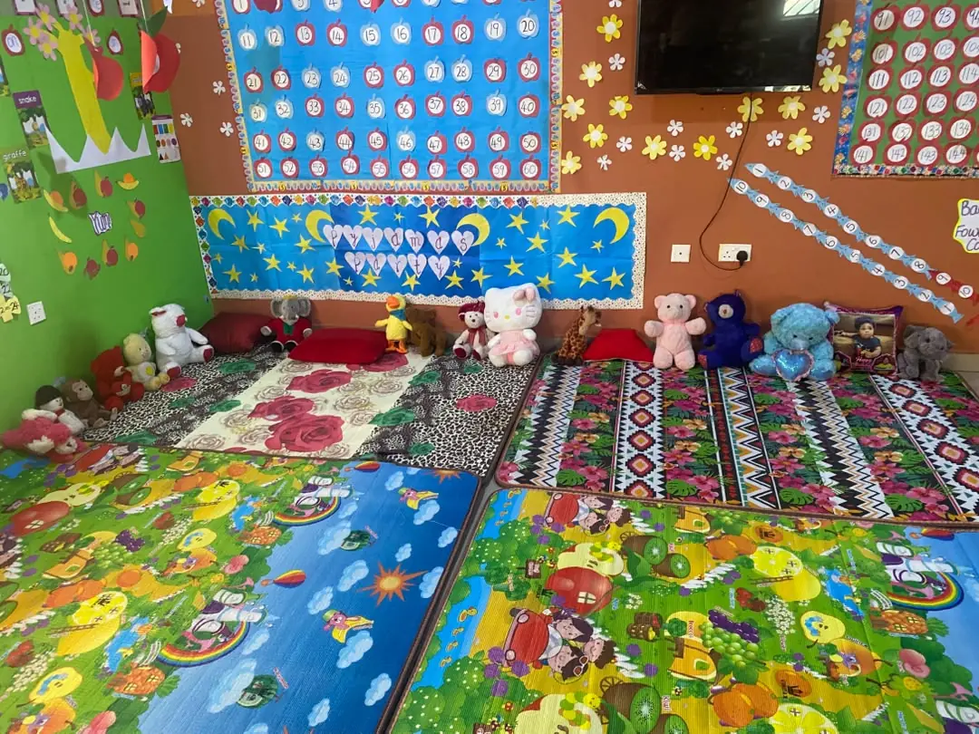 The creche playroom, with soft play mats, cushions and soft toys beneath colourful wall displays
