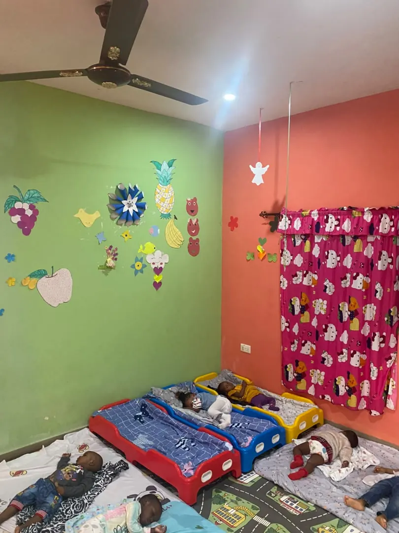 Young children resting on small cots in the creche nap room