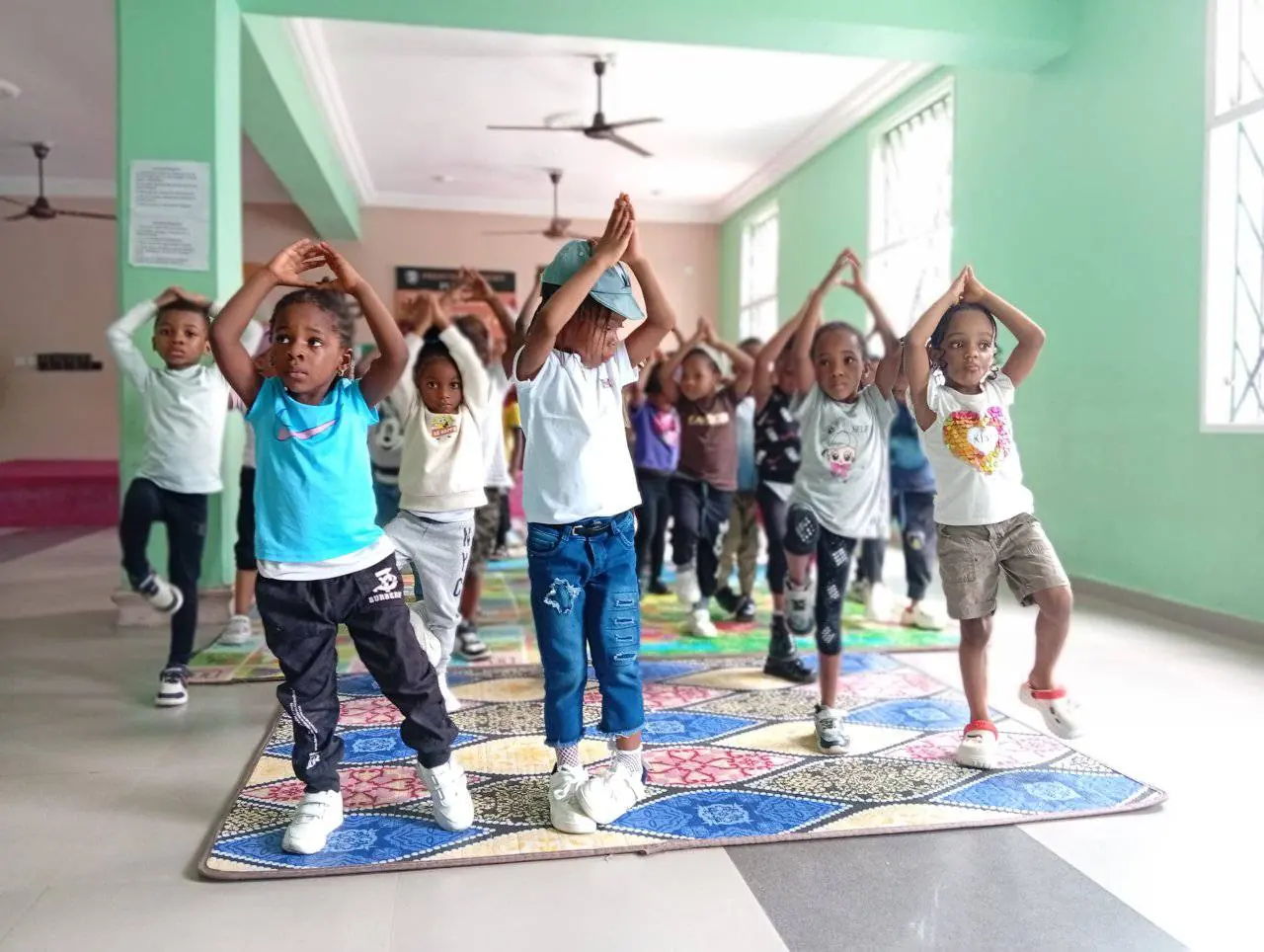 Young pupils holding a ballet pose with arms raised in a dance class