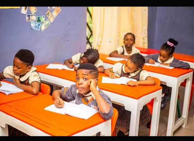 Pupils writing at orange-topped desks in a bright classroom