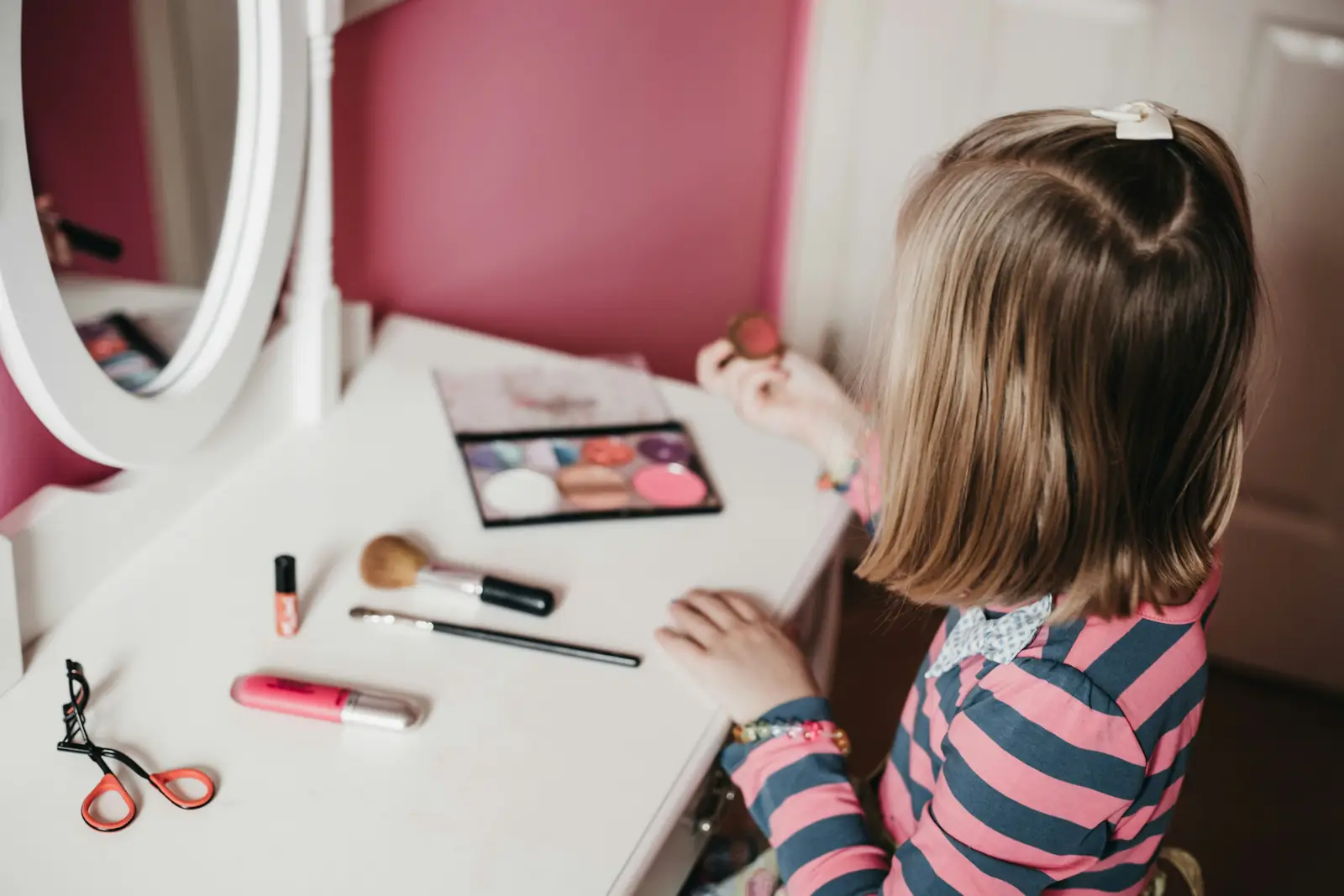 Illustrative photo: a child at a dressing table with make-up brushes and a palette