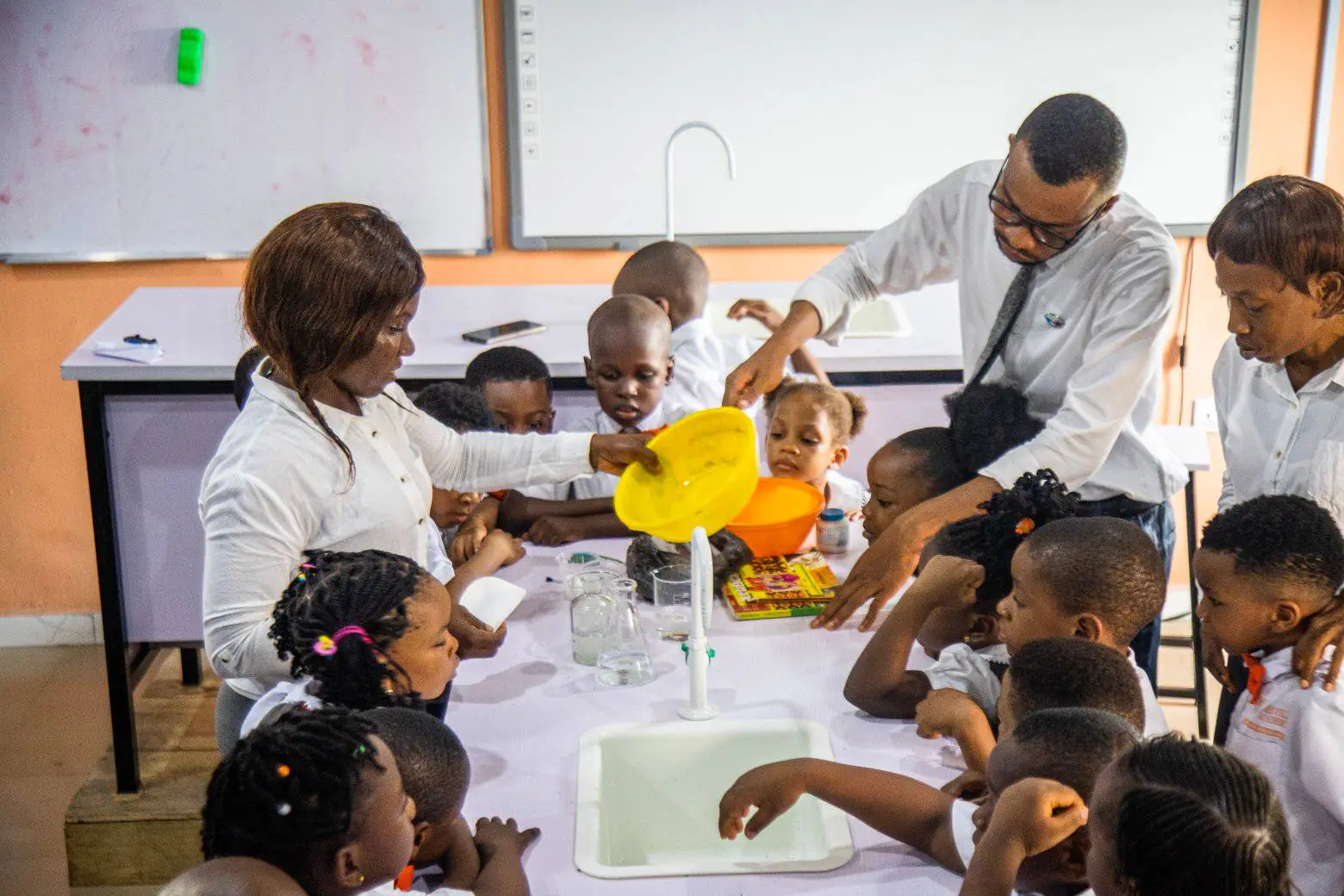 Grade School pupils gathered round a laboratory bench as their teachers demonstrate an experiment