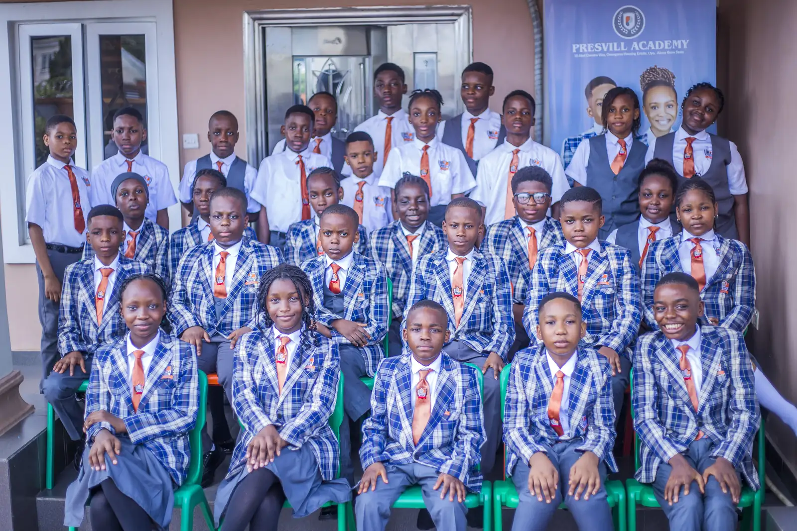 High School students in checked blazers and orange ties posed together for a group photograph