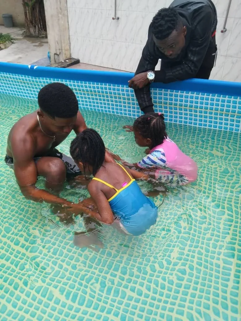 A swimming instructor in the pool with two young pupils during a lesson